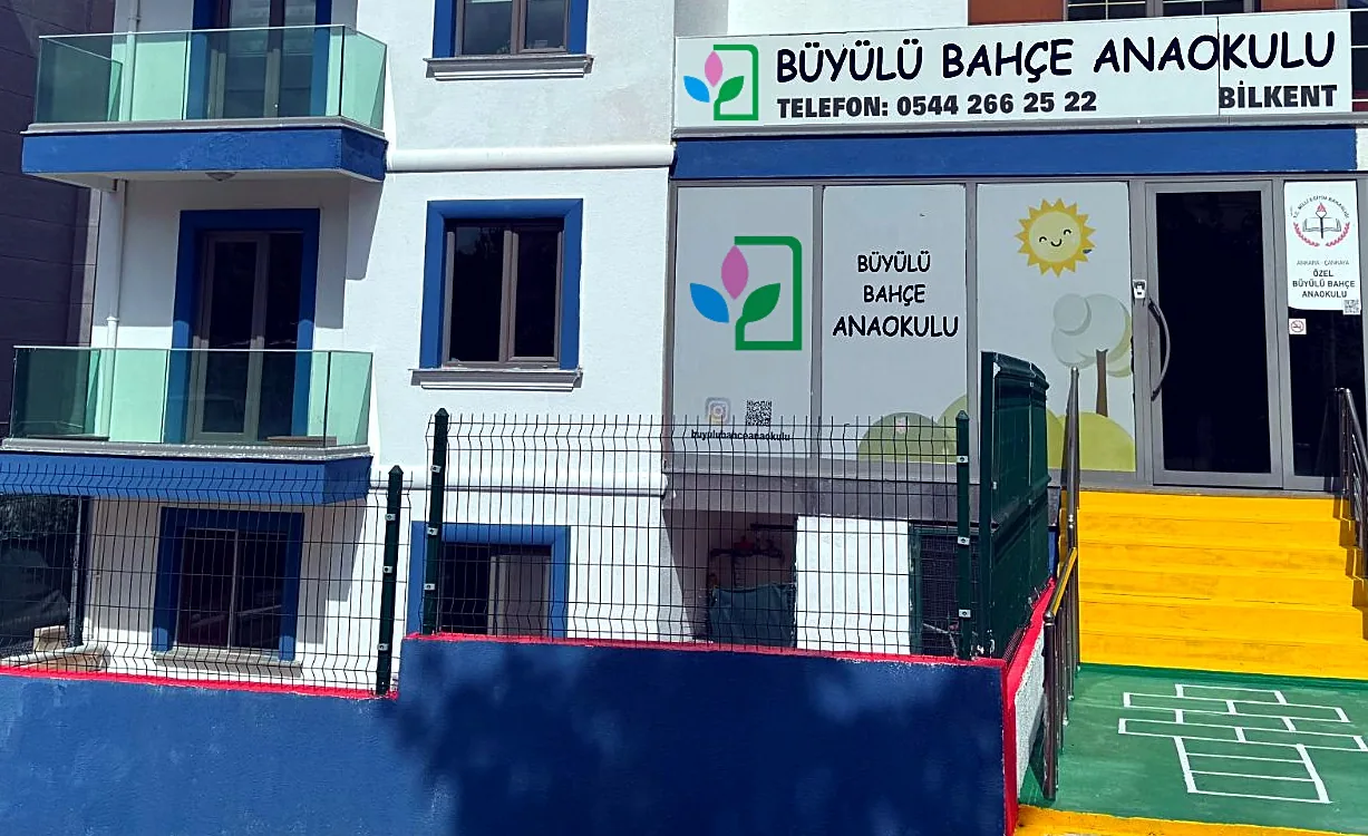 Büyülü Bahçe Anaokulu binasının girişi: tabela, okul kapısı ve sarı merdiven