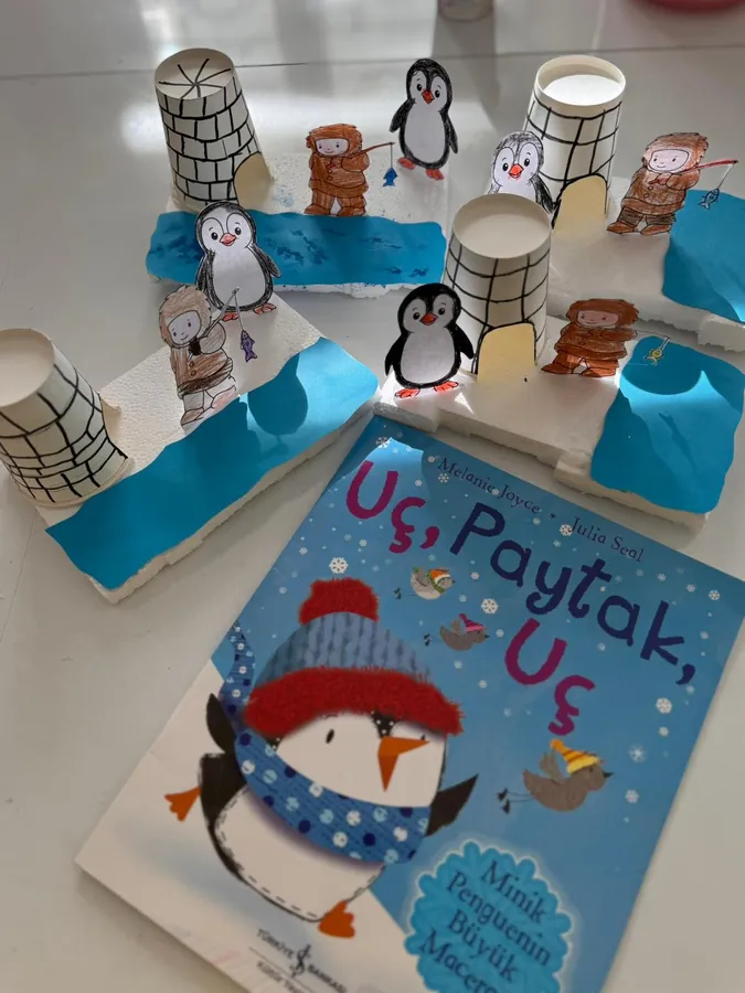 Kâğıt bardaktan iglo ve penguen maketi, yanında resimli kitap